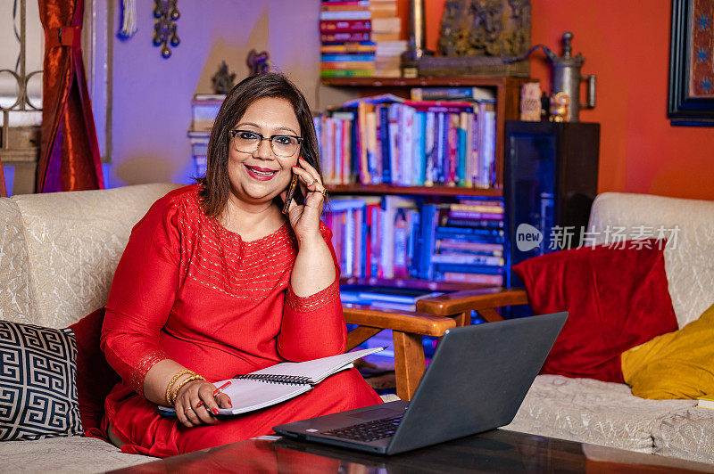 Happy senior woman working on laptop and using mobile phone at home.